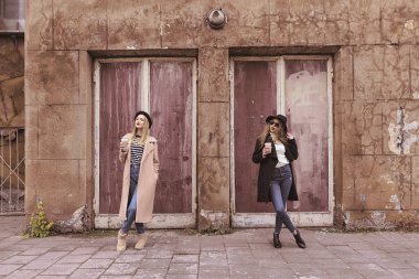 eski bir bina arka plan üzerinde kahve içme iki şık kız