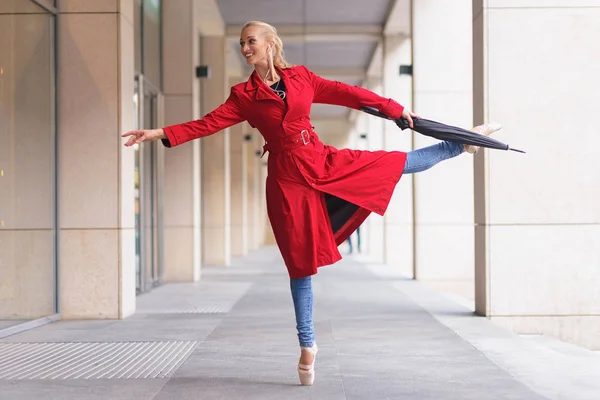 Bailarina com guarda-chuva numa mão. Quente dia de outono. Mulher de casaco vermelho e jeans azuis — Fotografia de Stock