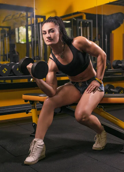 Brutal atlética mujer bombeando músculos con mancuernas — Foto de Stock
