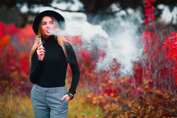 Vaping. Fiatal gyönyörű nő, a hat vaping, szabadban, őszi — Stock Fotó