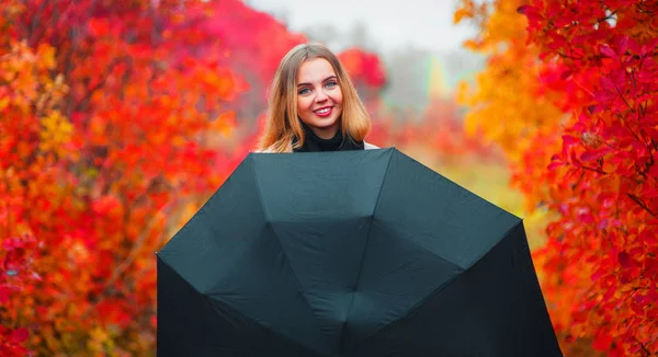 Uma garota com um guarda-chuva preto está se escondendo da chuva — Fotografia de Stock