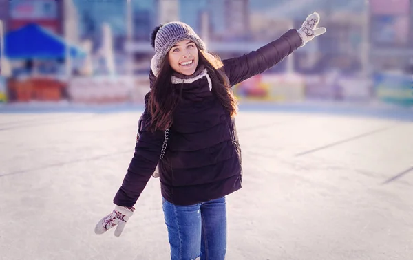 Young woman ice skating outdoors on ice rink in winter day