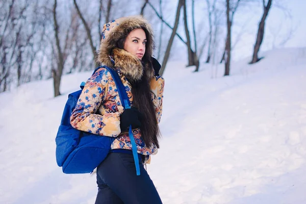 冬の森で時間を過ごす美しい若い女性。コートとバックパックを着用します。冬が来ている、初雪. — ストック写真