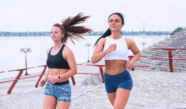 İki genç kadın sabah erken plajda yürüyor.