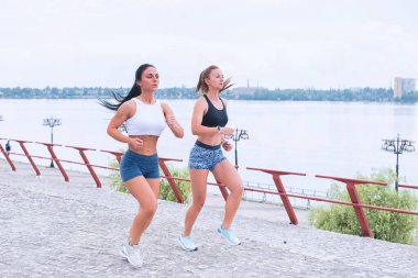 İki genç kadın sabah erken plajda yürüyor.