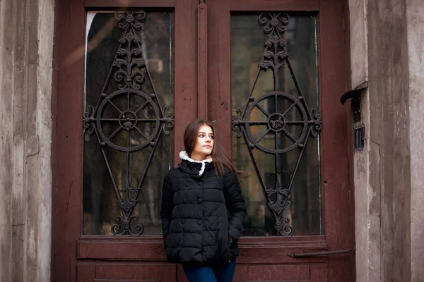Mujer joven está de pie delante de la vieja puerta de madera vintage — Foto de Stock
