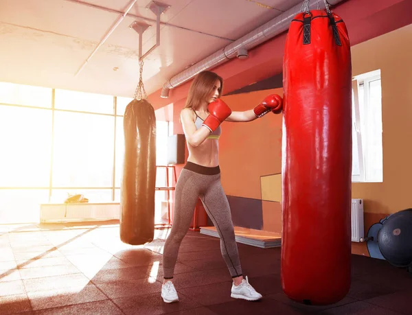Młode kobiety, boks, uderzając worek bokserski — Zdjęcie stockowe