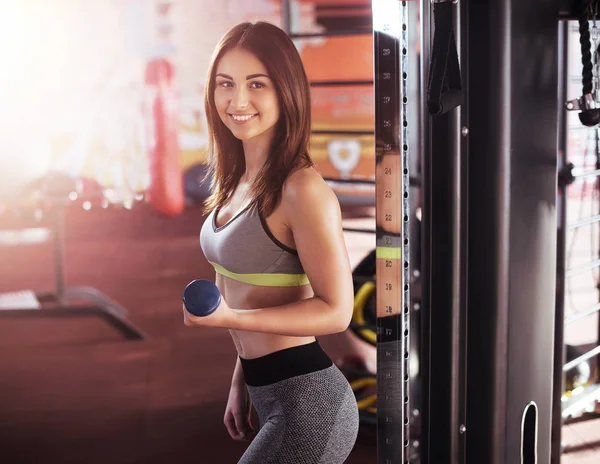 Fitness, esporte, treinamento, ginásio e conceito de estilo de vida - mulher sorridente trabalhando com halteres no ginásio — Fotografia de Stock