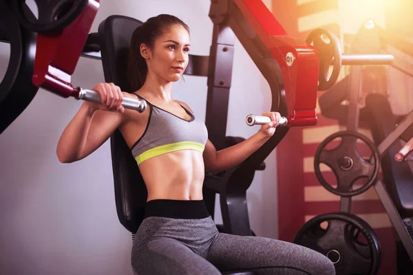 Jeune femme de fitness faire de l'exercice avec la machine d'exercice dans la salle de gym pendant la matinée. . — Photo