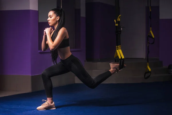 Mujer atractiva hace Crossfit con correas de fitness Trx en el estudio del gimnasio —  Fotos de Stock