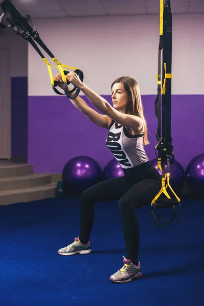 Attraktive Frau macht Crossfit Liegestütze mit Trageschlaufen im Studio des Fitnessstudios — Stockfoto