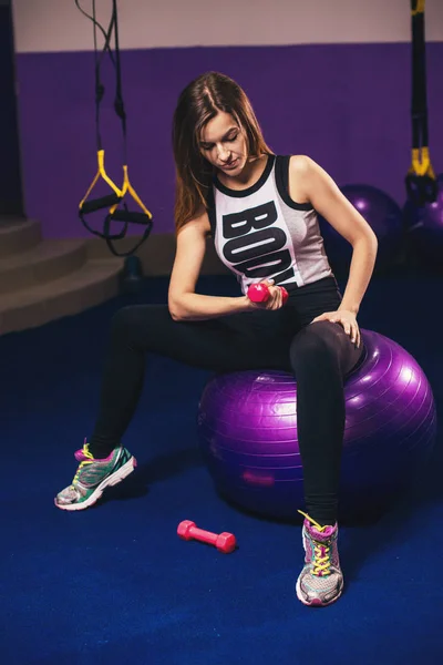Fitball üzerinde oturan ve dumbbells ile egzersizleri yapıyor kadın — Stok fotoğraf