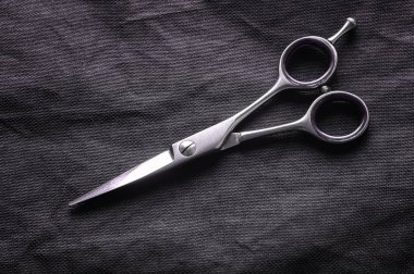 Close up of hairdressing scissor on black background. Shiny chrome barber scissors. clipart