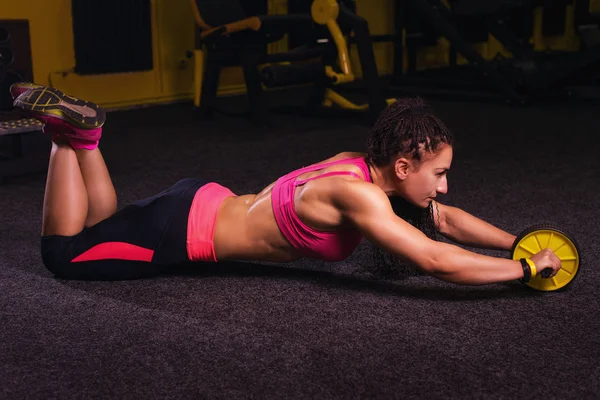 Mujer con hacer ejercicios abdominales con rueda. Ejercicio de entrenamiento en casa para perder peso — Foto de Stock