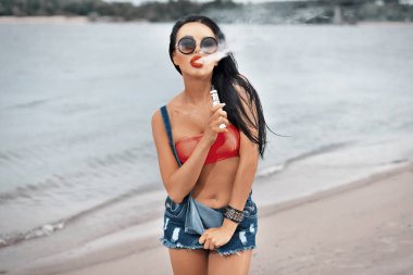 Genç güzel kadın vaping sigara duman açık havada ile. Buharı kavramı.