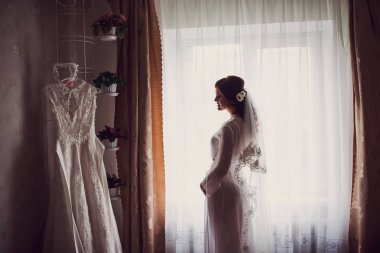 Gelin sabah hazırlık. Beyaz düğün sabahlık ve peçe büyük yatak odası penceresinin arka plan üzerinde güzel gelin