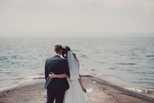 Bruidspaar zoenen en knuffelen op rotsen in de buurt van de blauwe zee — Stockfoto