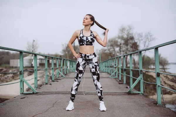 Genç atletik kadın stand şehir köprüsü üzerinde sportif kadın sabah saat çalışan