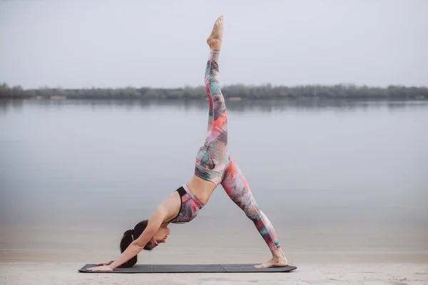 Yoga matutino y pilates. Joven mujer sana practicando yoga en la playa al amanecer . — Foto de Stock