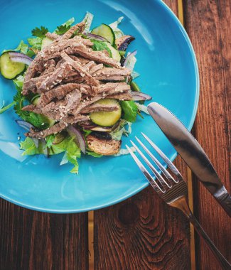 Dana salatası marul, elma, armut ve koyu ahşap arka plan, kopya alanı üzerinde mavi plaka üzerinde. Restoran gıda, yakın. Et salatası