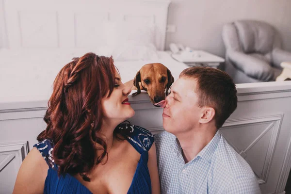 Familia joven, mujer embarazada y su pareja o marido con perro sentado en el suelo —  Fotos de Stock