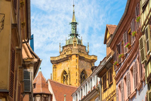 Utsikt över ett hus front med gamla korsvirkeshus och färgglada fönsterluckor och en vacker utsikt över katedralen i bakgrunden i den vackra gamla franska staden Colmar i regionen Alsace. — Stockfoto