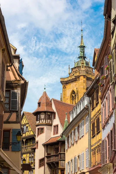 Udsigt over beboelsesejendomme af gamle bindingsværkshuse og farverige vinduesskodder og en smuk udsigt over "St. Martins Kirke" i baggrunden i den smukke gamle franske by Colmar i Alsace . - Stock-foto