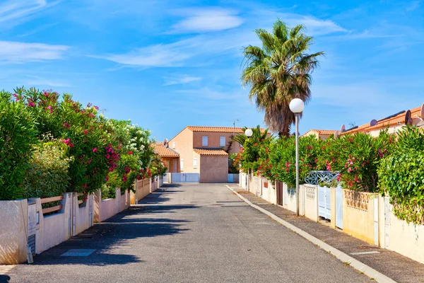 En gata och gångbanor i semesterorten Les Ayguades i Gruissan, södra Frankrike med utsikt över de vackra färgglada trädgårdarna — Stockfoto