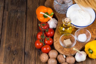 Resmi sol kısmında kopya alanı ile zeytin ahşap bir pizza hamuru ve pizza tepesi bir ahşap tahta üzerinde taze malzemelerle yapılan