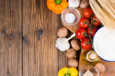 Resmi sol kısmında kopya alanı ile zeytin ahşap bir pizza hamuru ve pizza tepesi bir ahşap tahta üzerinde taze malzemelerle yapılan