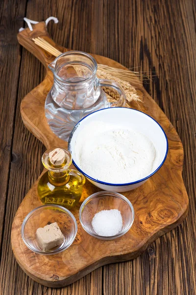 Ingredienser för en pizzadeg på en träskiva tillverkad av olivträ på rustika trä bakgrund — Stockfoto