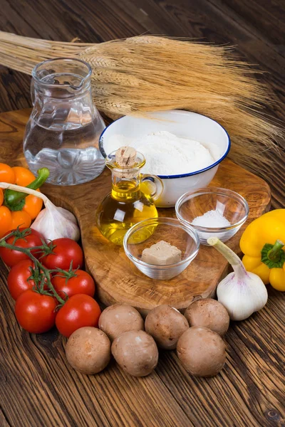 Fresh ingredients for a pizza dough and the pizza topping a wooden board made of olive wood with copy space in the lower part of the picture — Stock Photo, Image