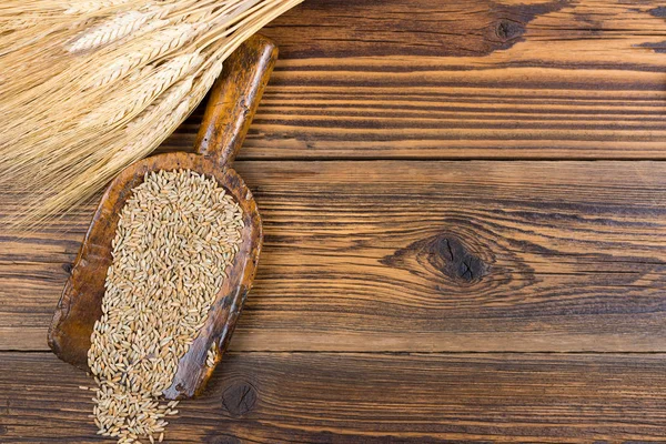 古い小麦粉シャベル粒は画像の右側の部分にコピー スペースを持つ素朴な木製の背景に乾燥した穀物の耳 — ストック写真
