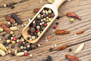 Rustik ahşap arka plan ile daha fazla baharat baharat vurgunun üzerinde renkli peppercorns closeup