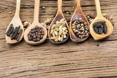 Beş ahşap yemek kaşık üst üste daha fazla baharat ve kopya alanı bir rustik ahşap zemin üzerine çeşitli egzotik baharatlar ile closeup