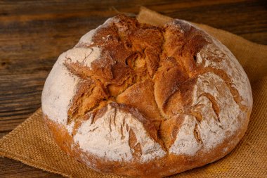 A fresh whole grain bread from the baker on a jute fabric on a rustic wooden background