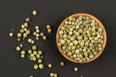 Siyah arka planda yeşil biberlerle dolu küçük bir ahşap kase. Yaklaş, üst manzara.