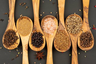 Baharat ve Gıda - Siyah arka planda zeytin ağacından yapılmış yemek kaşıklarındaki çeşitli baharatlardan yapılmış arka plan