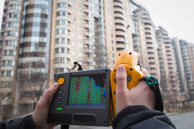 Man is pushing a thermal scope to a heated apartment building in search of heat leakage in a warmed building in central Kiev, Ukraine clipart