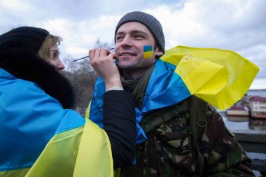 Kiev, Ukrayna - 22 Ocak 2017: Bir kadın Kiev, Ukrayna birlik günü kutlamaları sırasında Ukrayna ulusal bayrak bir adamın yüzünde renk boyalar.