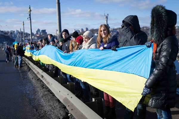 KIEV, UKRAINE - January 22, 2017: People carry national flags on a bridge while forming a human chain across the Dnieper river during celebrations for Unity Day in Kiev, Ukraine.