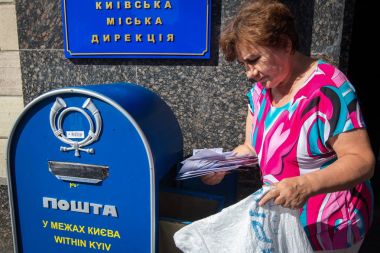 The postman pulls letters from the mailbox near the main post office in Kiev, Ukraine clipart