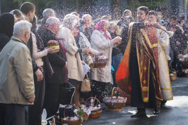 Ukraynalı Ortodoks rahip sprinkles kutsal su müminler Ortodoks Paskalya hizmet Kiev, Ukrayna Volodymysky katedralde dışında arifesinde