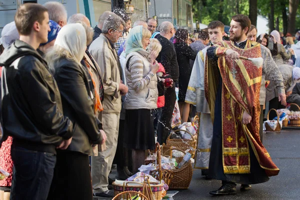 Ukraiński prawosławny kapłan kropi wodą święconą na wierzących w przeddzień Wielkanoc prawosławna usługi poza katedry Volodymysky w Kijowie, Ukraina — Zdjęcie stockowe