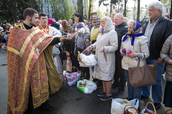 Ukraiński prawosławny kapłan kropi wodą święconą na wierzących w przeddzień Wielkanoc prawosławna usługi poza katedry Volodymysky w Kijowie, Ukraina — Zdjęcie stockowe