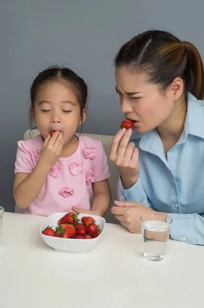 พ่อแม่และลูกกําลังกินสตรอเบอร์รี่อย่างมีความสุข . — ภาพถ่ายสต็อก