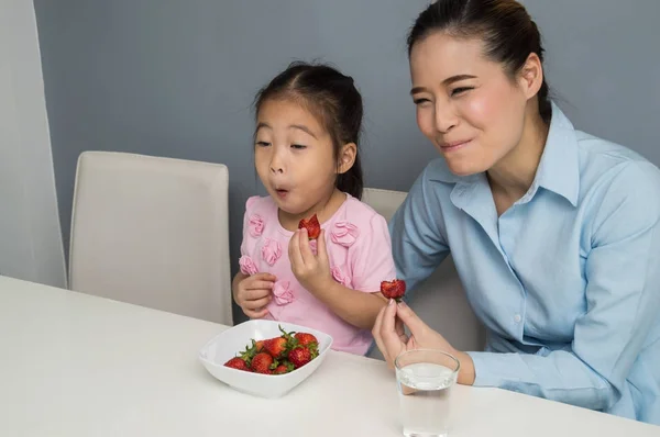 Pais e filhos estão comendo morangos alegremente . — Fotografia de Stock