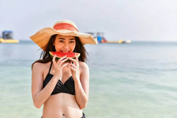 Gyönyörű lány visel fürdőruhát enni görögdinnye beach. — Stock Fotó