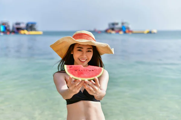 Gyönyörű lány visel fürdőruhát enni görögdinnye beach. — Stock Fotó
