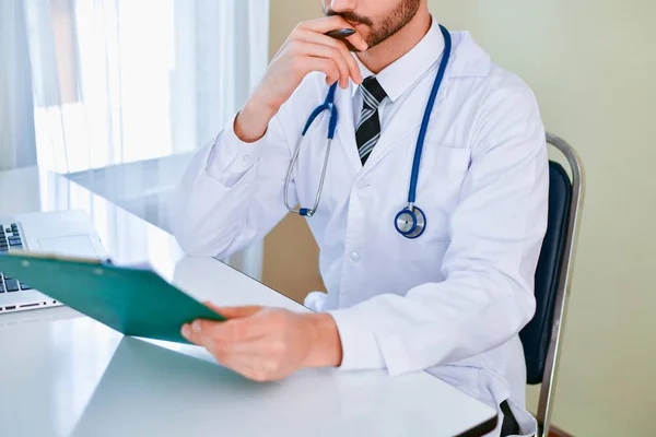 Docteur souriant posant dans le bureau, il porte un stéthoscope — Photo